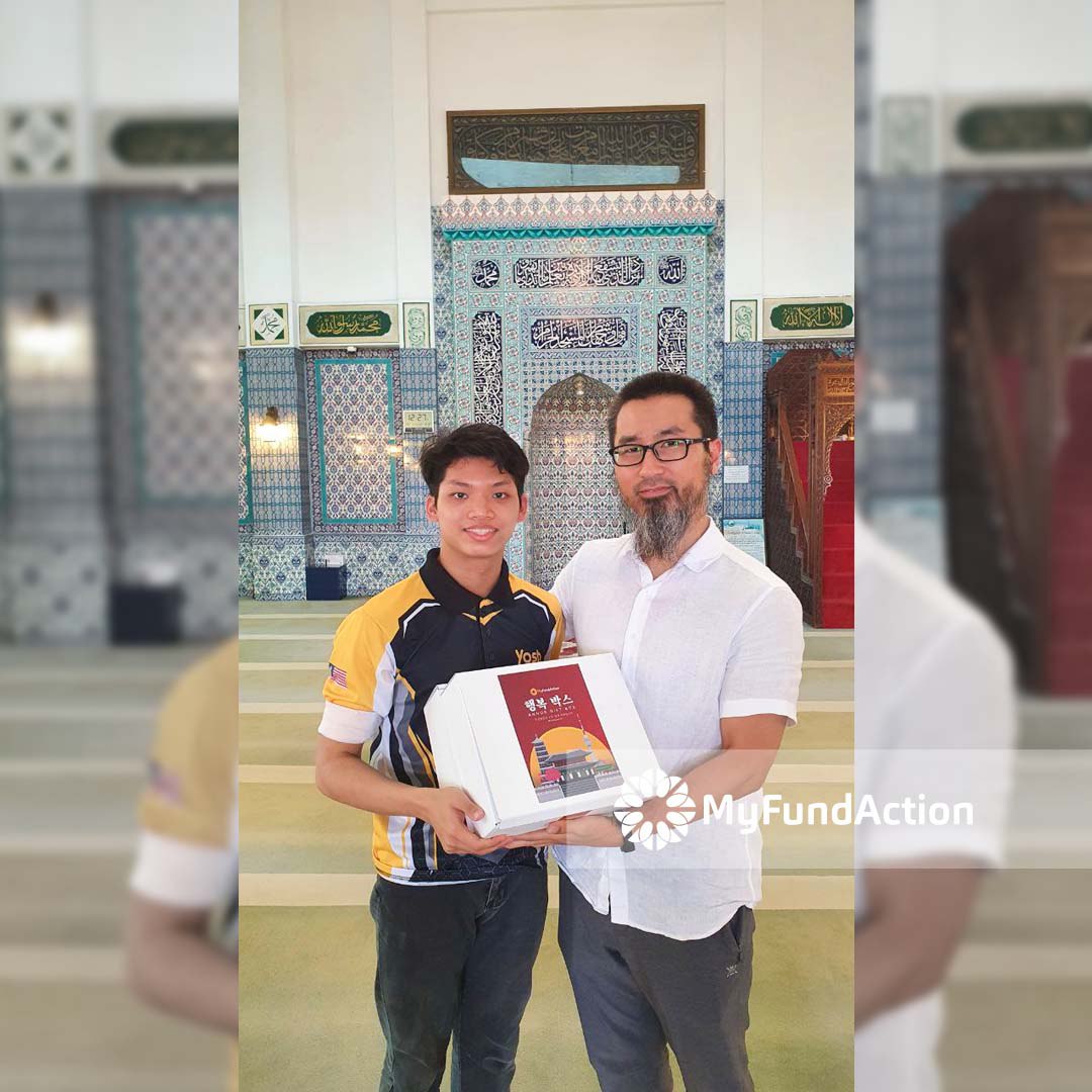 Two men, a representative of MyFundAction and a native Muslim Korea, holding haengbok box, which is a box that aims to support Muslims in Korea, especially the new reverts. 